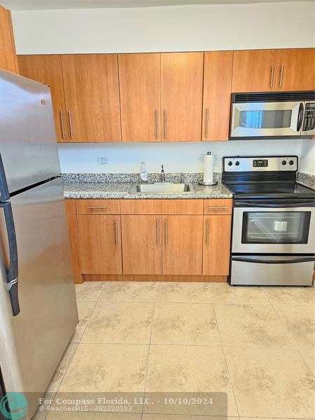 a kitchen with granite countertop a refrigerator and a stove