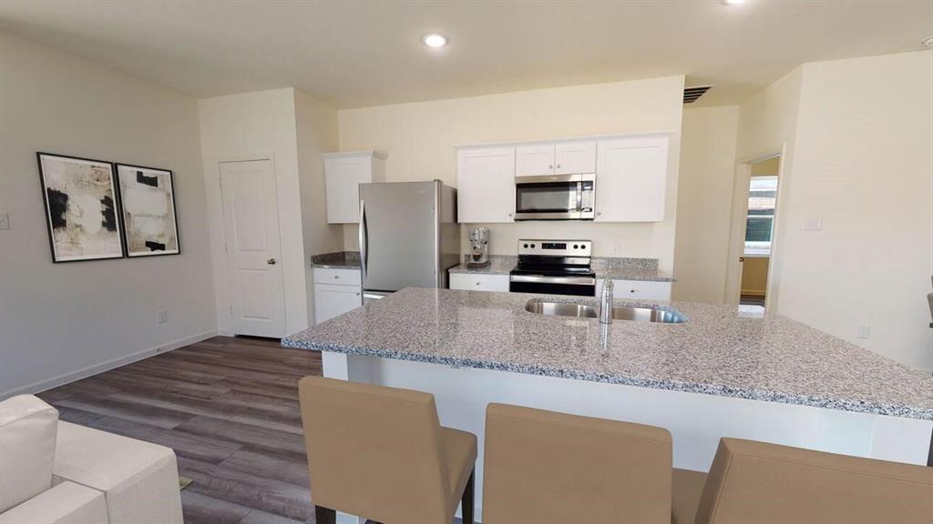 a kitchen with granite countertop a refrigerator and a stove top oven