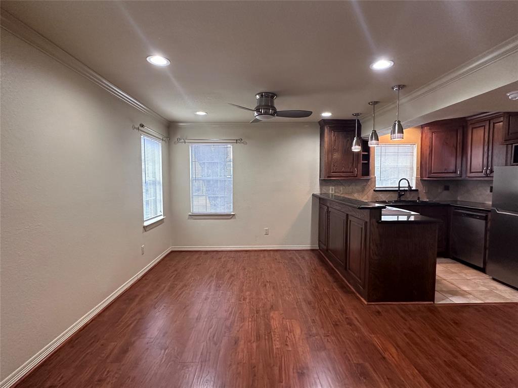 an open kitchen with wooden floor and black stainless steel appliances