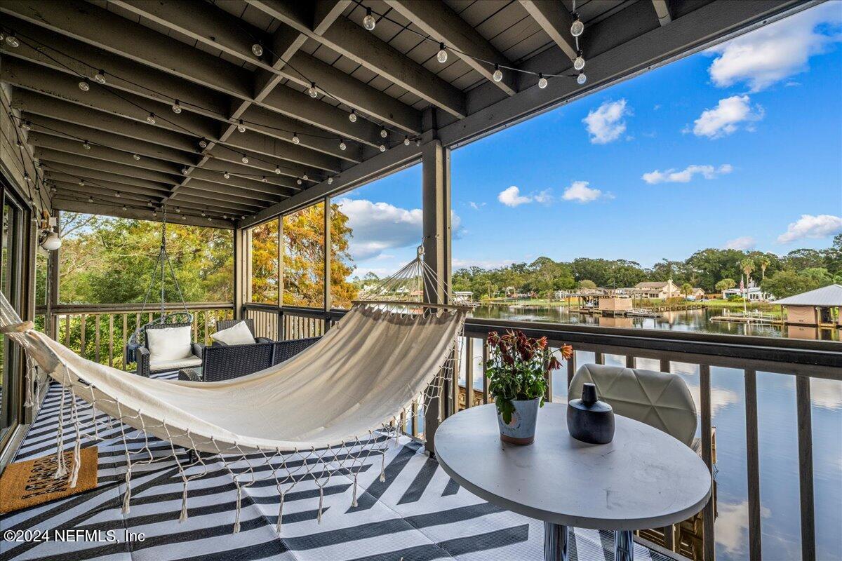 a view of roof deck with dining table and chairs with wooden floor and fence