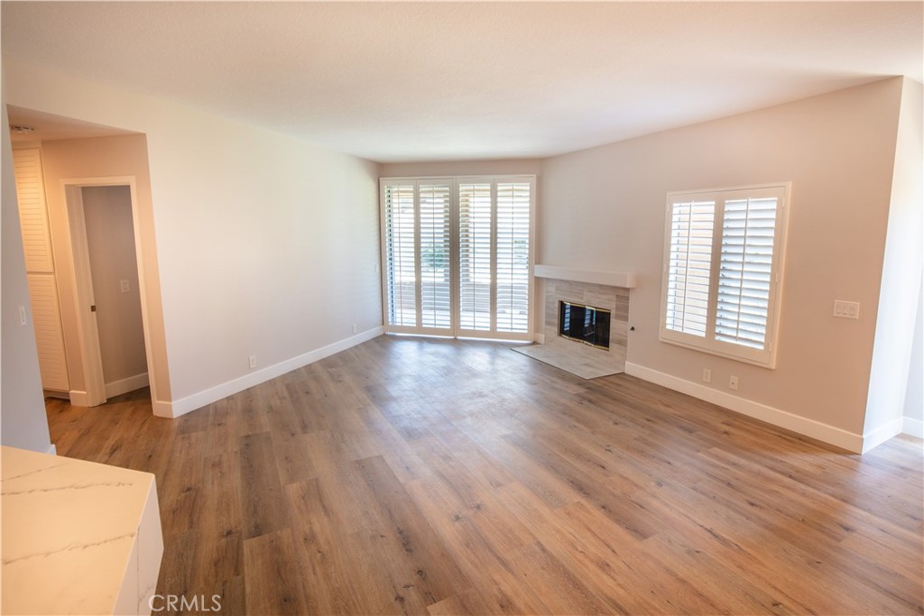 an empty room with wooden floor fireplace and windows