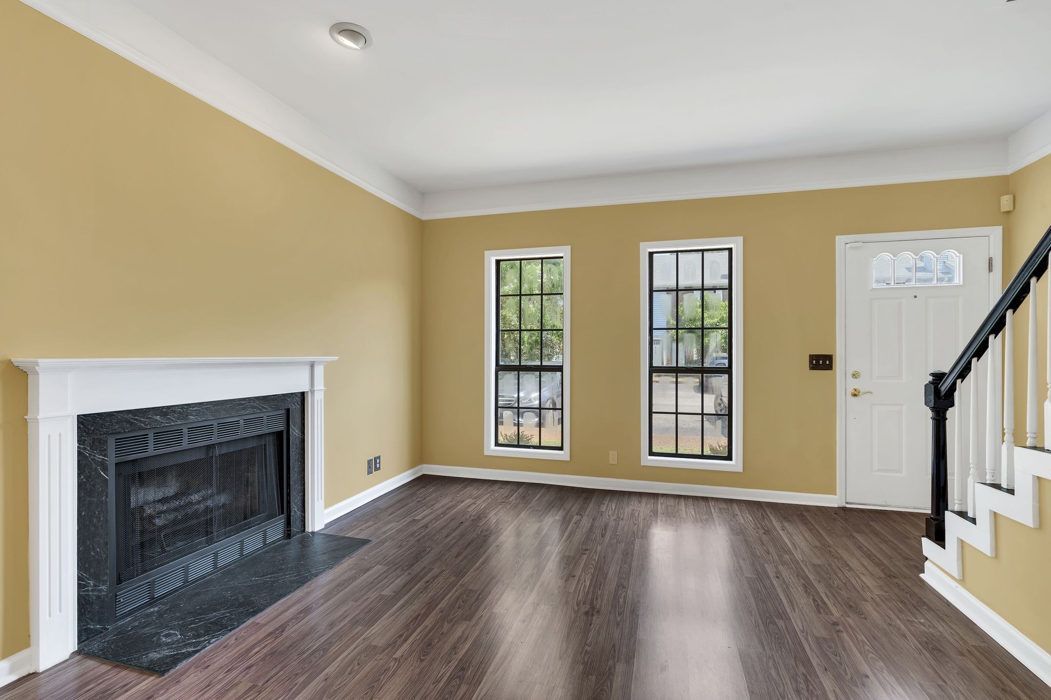 a view of an empty room with wooden floor fireplace and a window