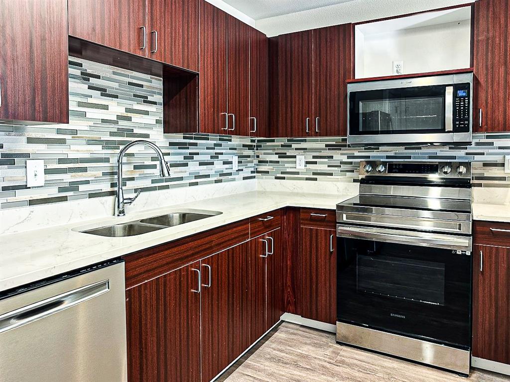 a kitchen with granite countertop a sink stove and microwave