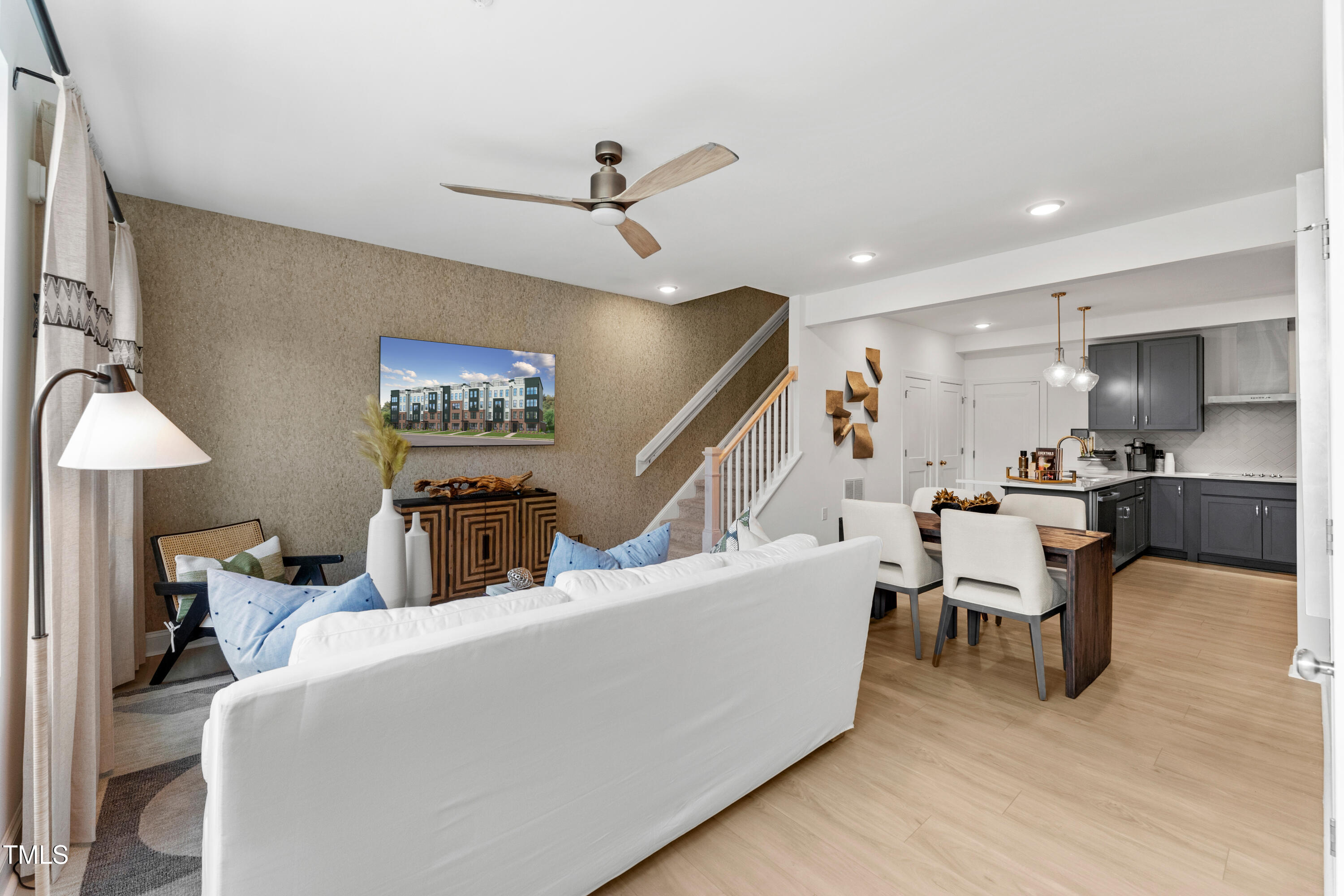 a living room with furniture kitchen view and a wooden floor