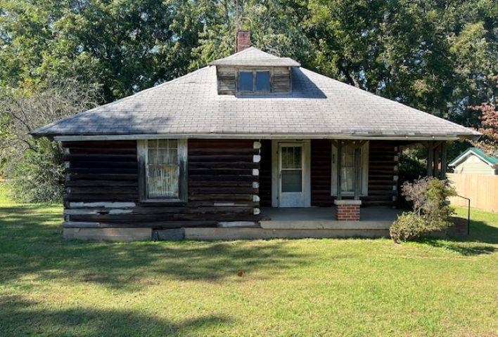 Log home featuring covered porch and a front lawn