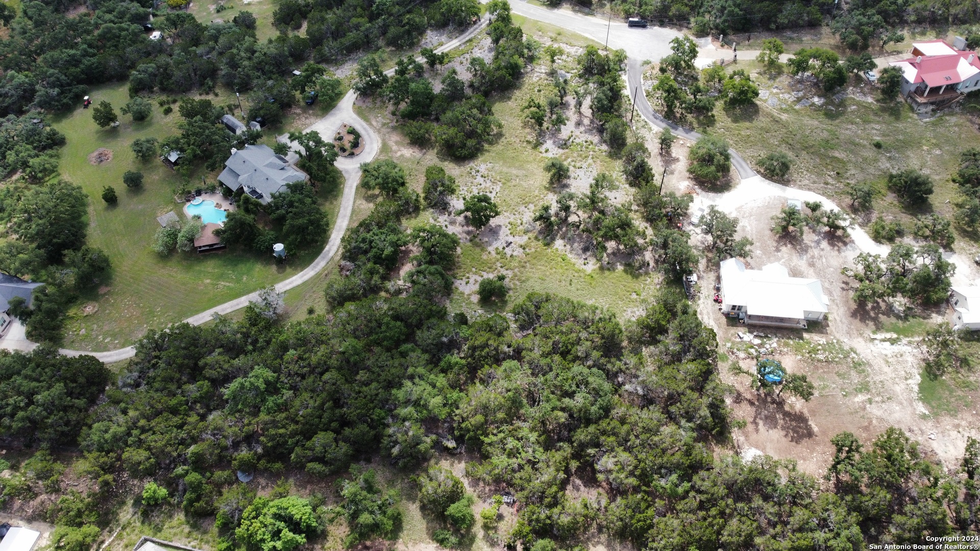 an aerial view of residential houses with outdoor space and trees