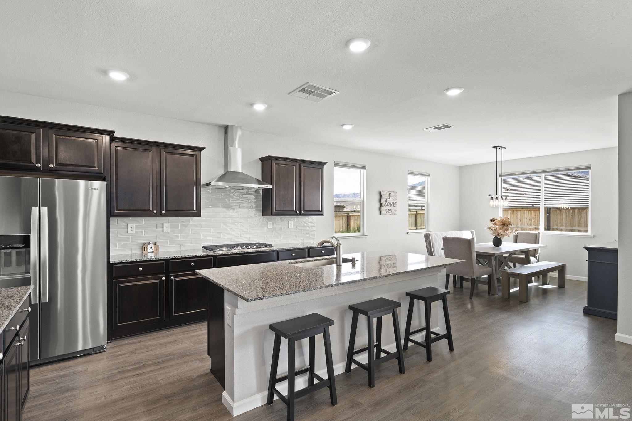 a kitchen with stainless steel appliances granite countertop a table chairs sink refrigerator and cabinets