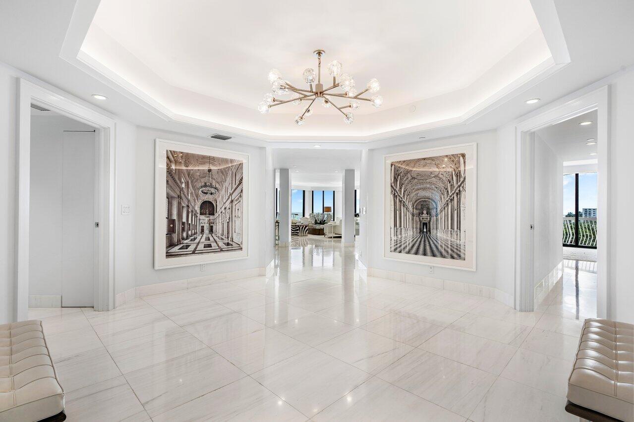 a view of a hallway with furniture and a chandelier fan