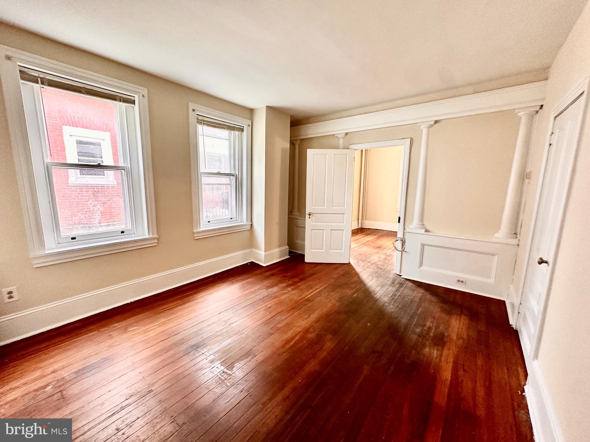 a view of an empty room with wooden floor and a window