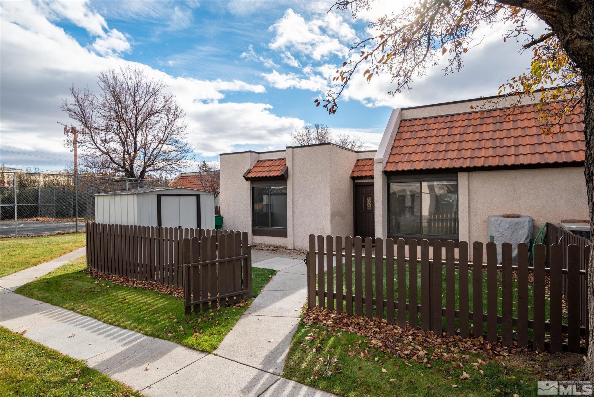 a view of a house with wooden fence next to a yard