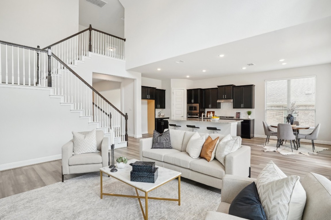 a living room with furniture kitchen view and a wooden floor