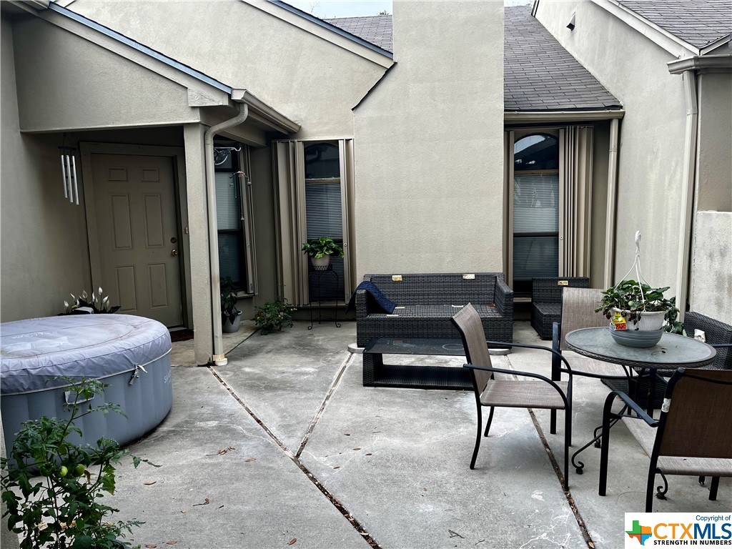 a patio with table and chairs and potted plants