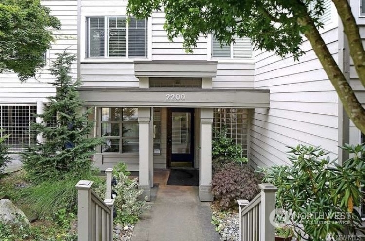 a view of a house with potted plants and a large tree