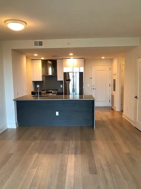 a view of a kitchen with kitchen island a sink wooden floor and a counter top space