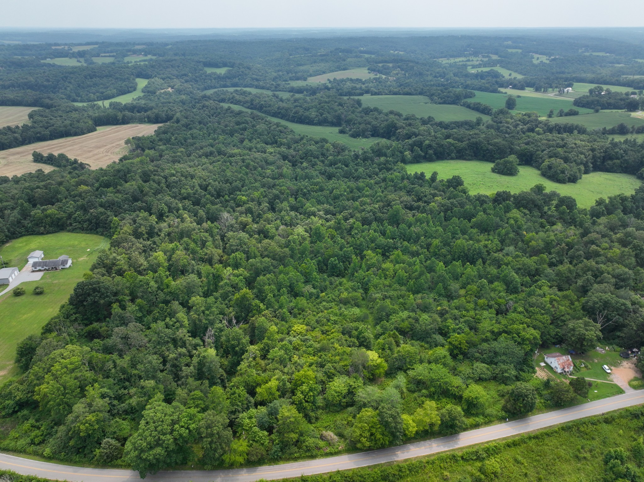 an aerial view of residential house with outdoor space and trees all around