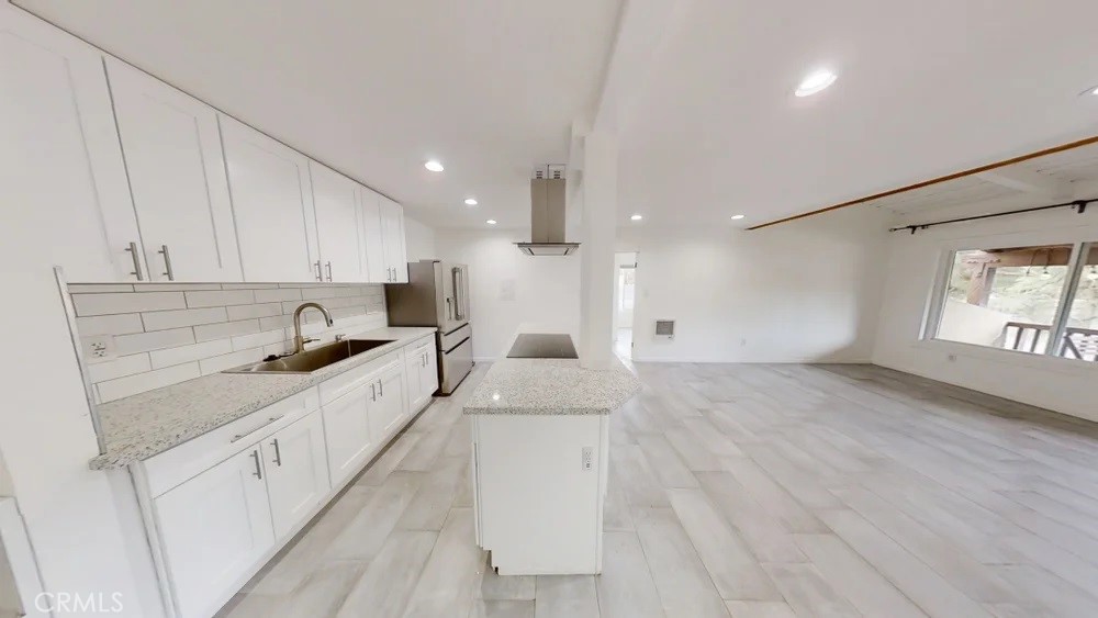 View of the kitchen and living room. New countertops, large sink and induction stove. Owner installed new in unit clothes washer and dryer and countertop dishwasher to the left of the sink after pictures were taken.