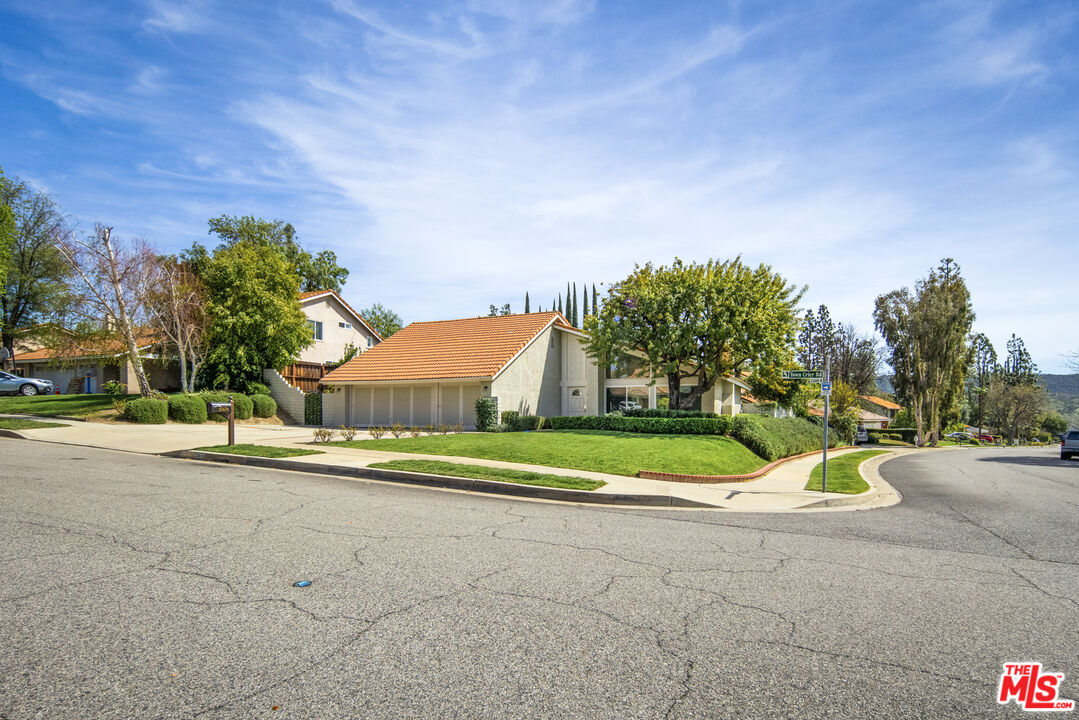 a view of yellow house with a big yard and large trees