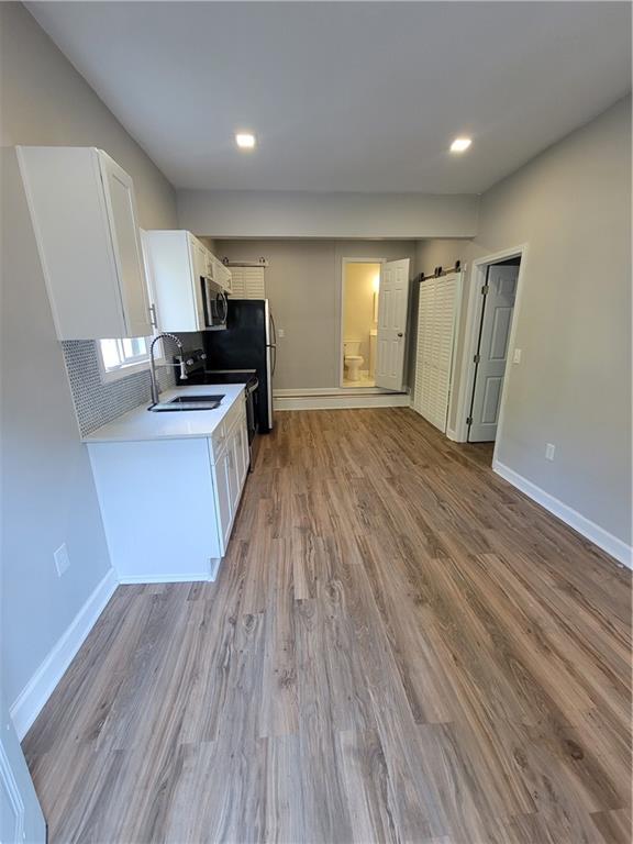 a view of kitchen with wooden floor electronic appliances and window