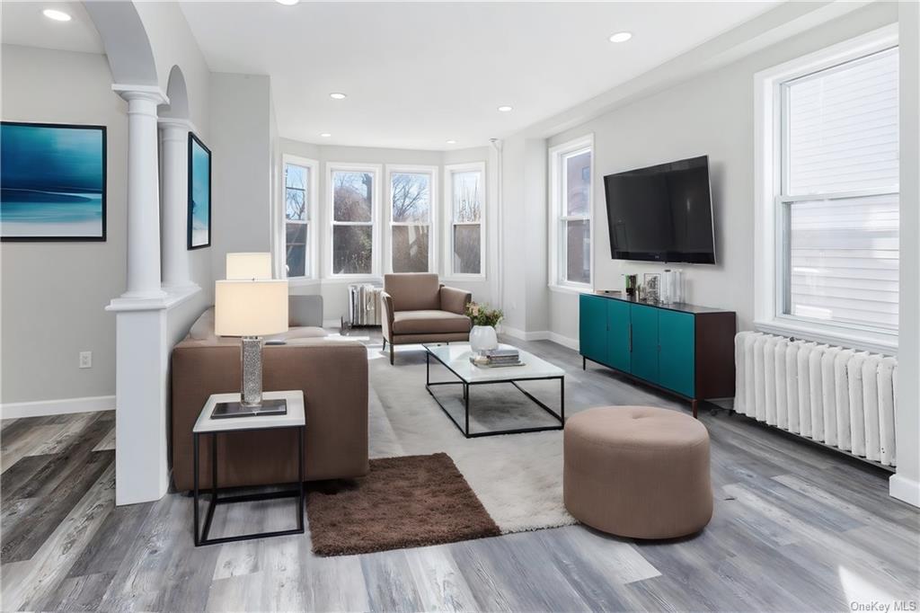 Living room with radiator heating unit, ornate columns, and hardwood / wood-style flooring