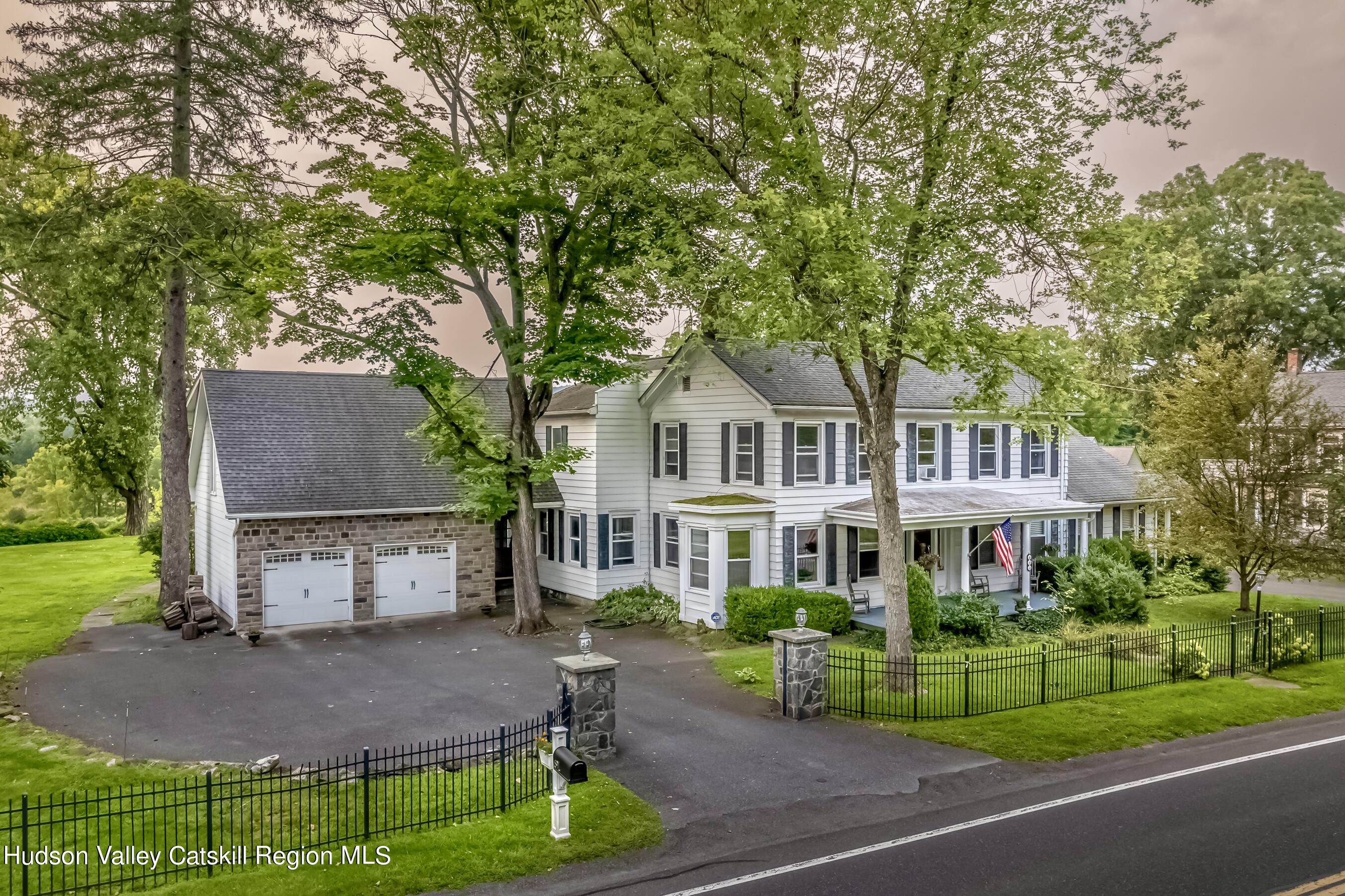 a front view of a house with a garden and trees