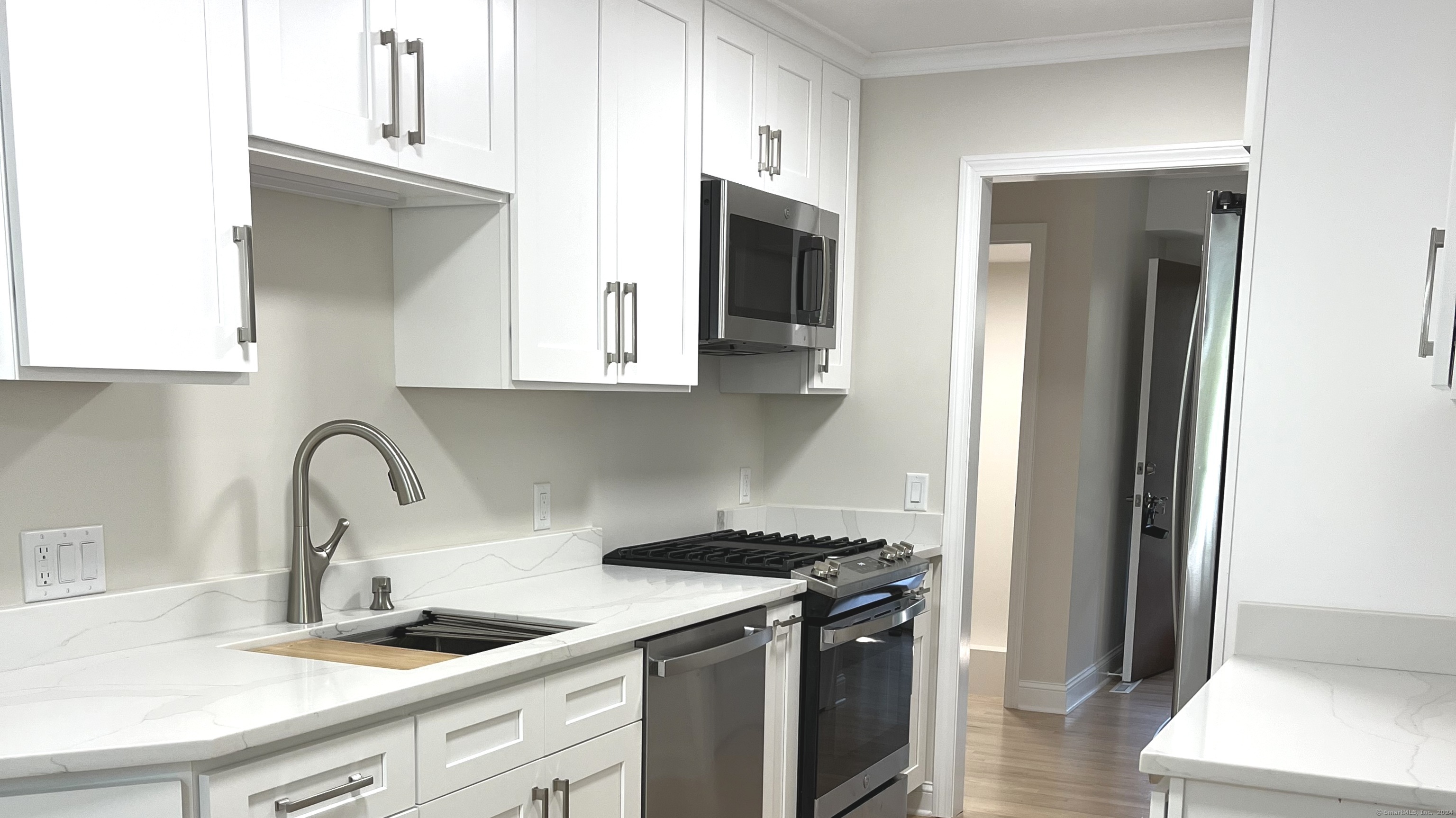 a kitchen with stainless steel appliances granite countertop a sink and a stove top oven with wooden floor