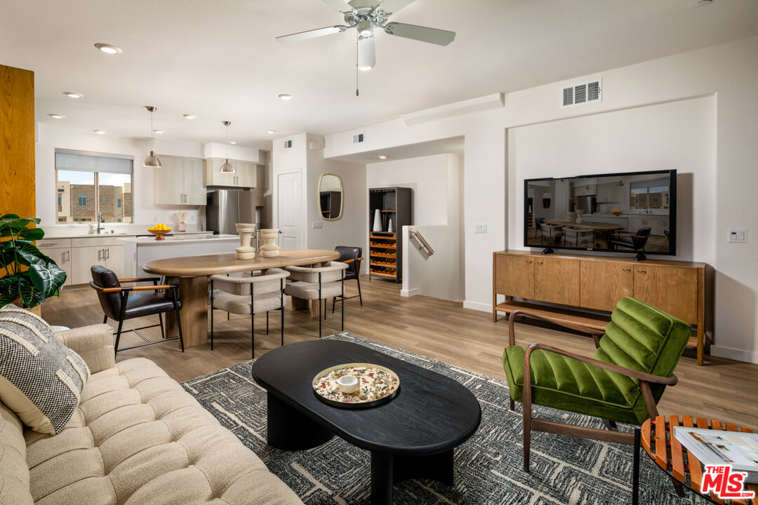 a living room with furniture a flat screen tv and kitchen view