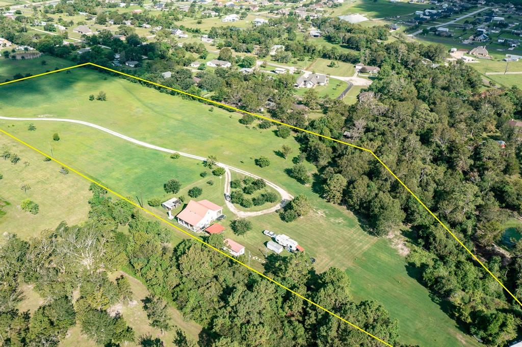 an aerial view of a residential houses with outdoor space and trees all around