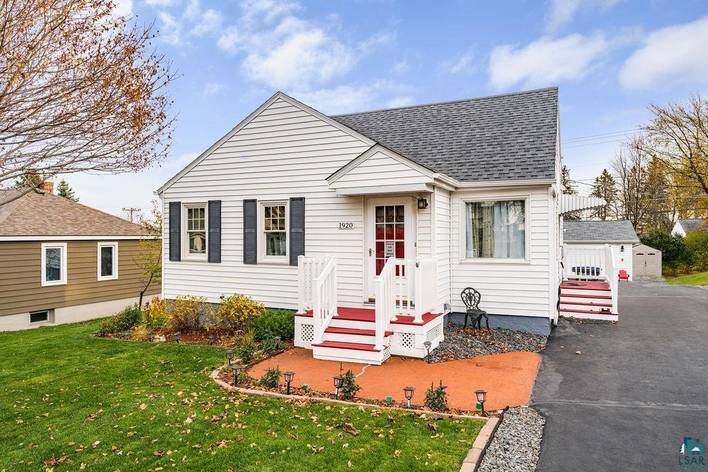 Bungalow featuring a garage, an outdoor structure, and a front lawn