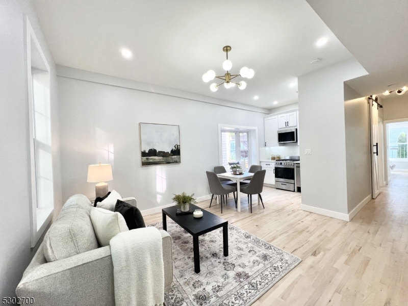 a living room with furniture kitchen view and a wooden floor