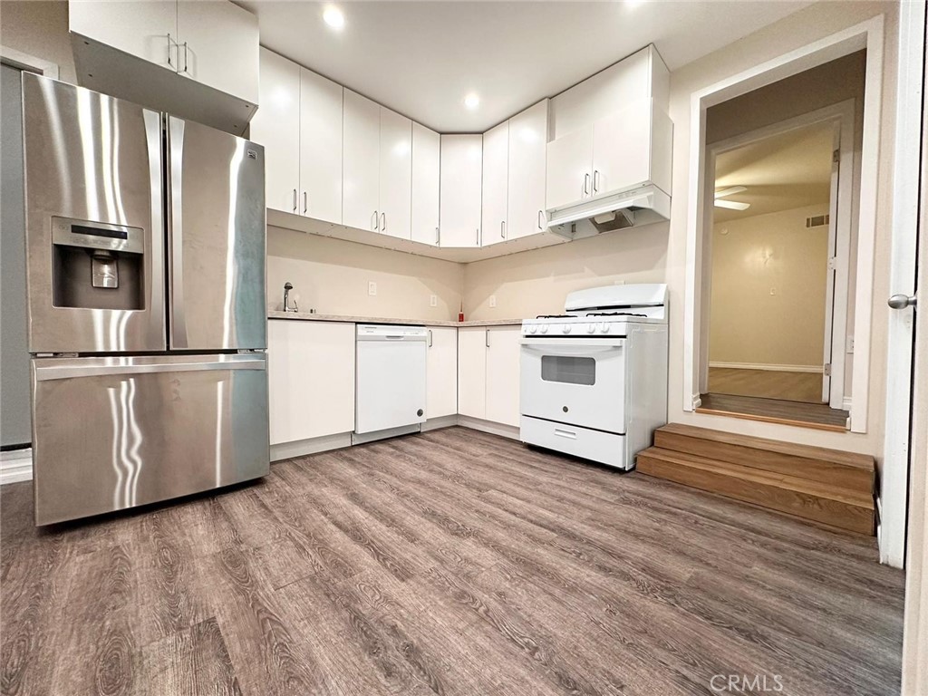 a kitchen with granite countertop a refrigerator and a stove top oven