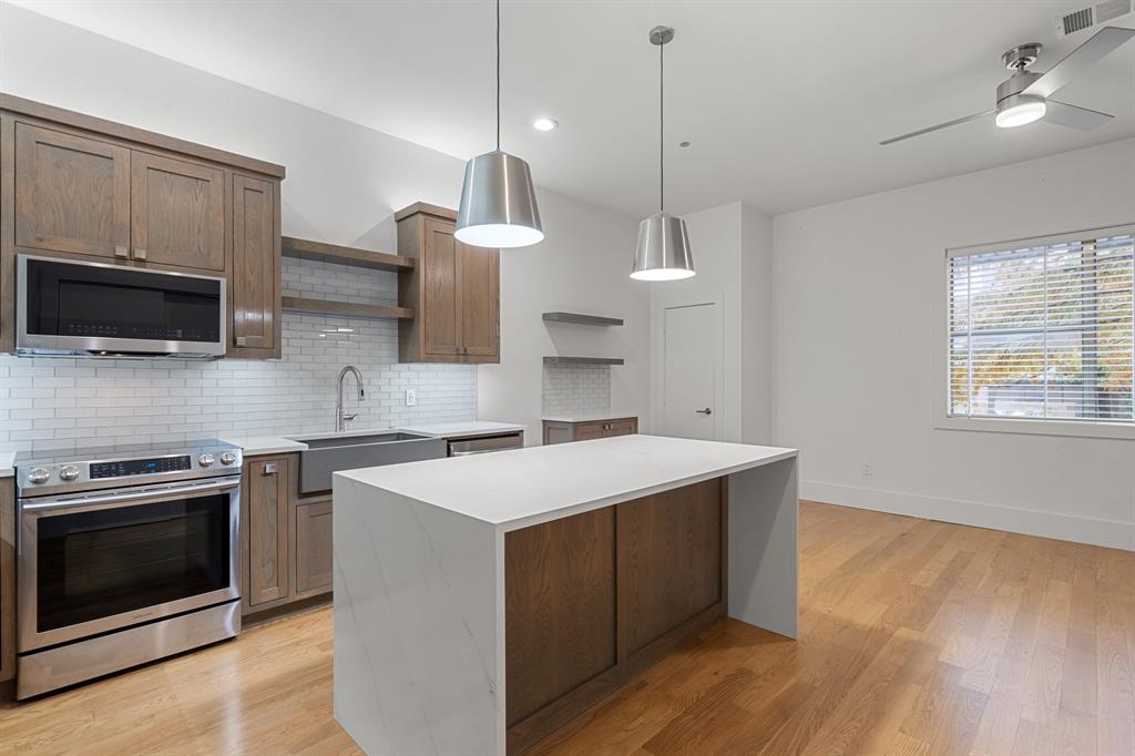 a kitchen with kitchen island a stove a sink and a wooden floor