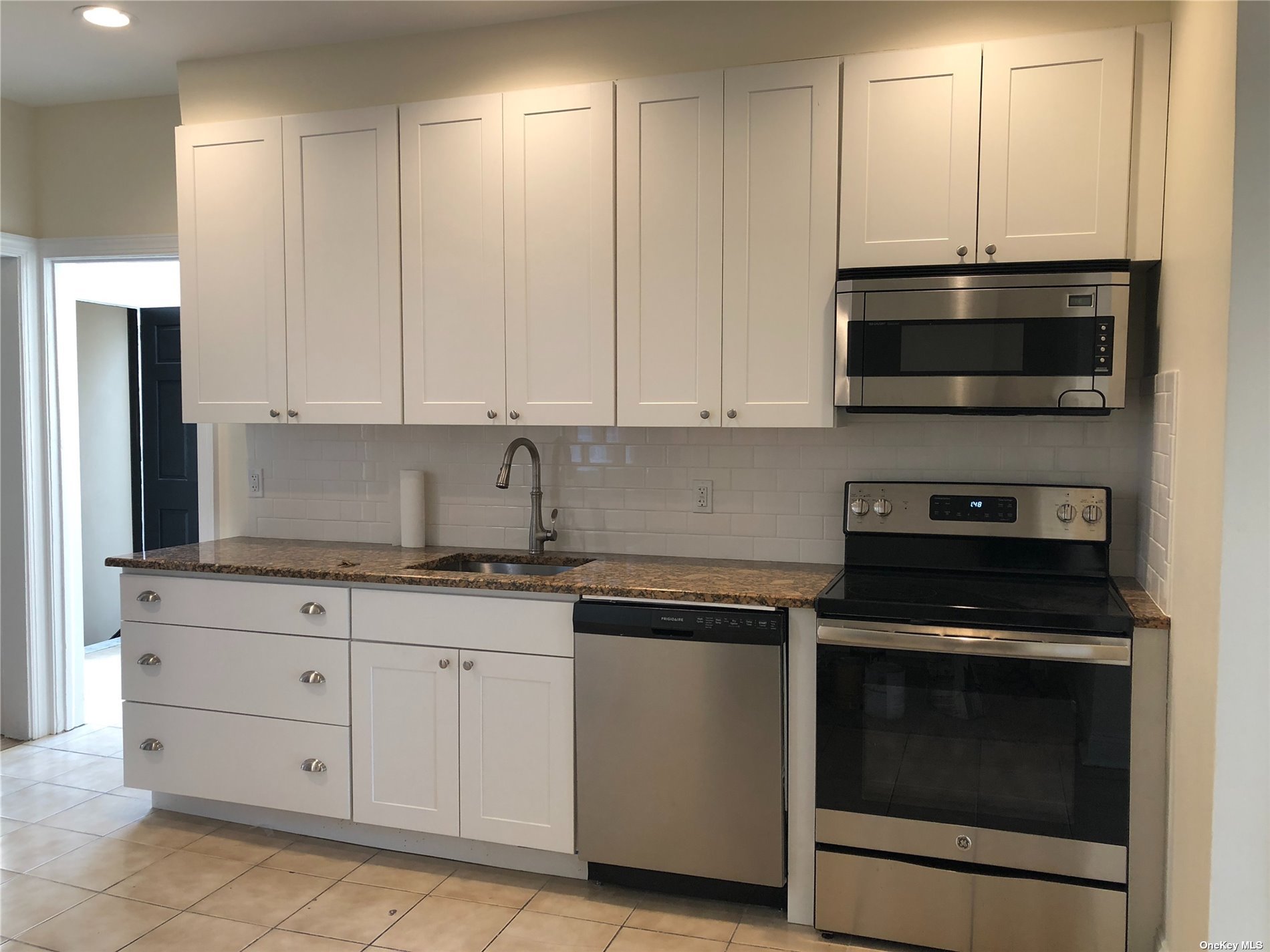 a kitchen with granite countertop white cabinets and stainless steel appliances