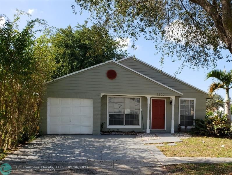 a front view of house with yard and trees in the background