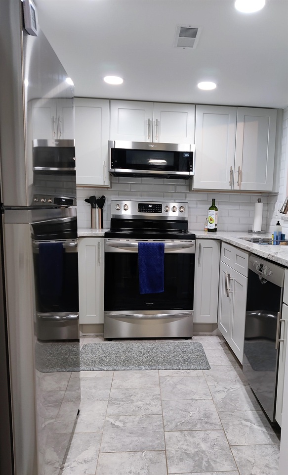 a kitchen with stainless steel appliances granite countertop a stove a sink and a microwave