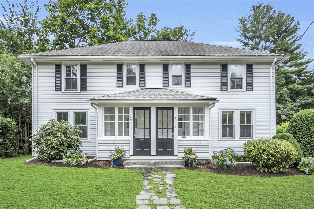 a front view of a house with a yard and potted plants