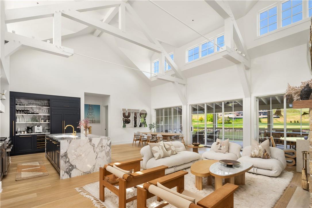 Living room with high vaulted ceiling, a wealth of natural light, and light hardwood / wood-style flooring