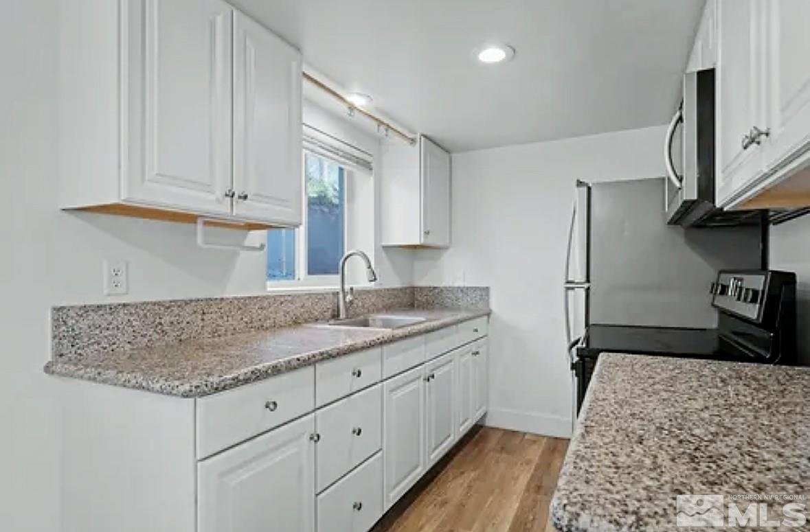 a kitchen with granite countertop a sink stove and cabinets