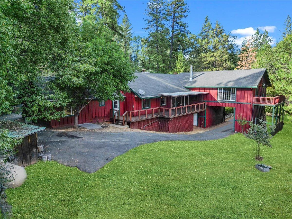 a view of a house with a yard deck and a large tree