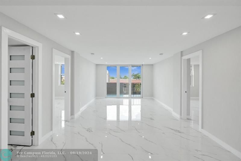 a view of a hallway with wooden floor and kitchen space