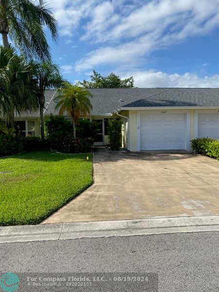 front view of house with a yard and palm trees