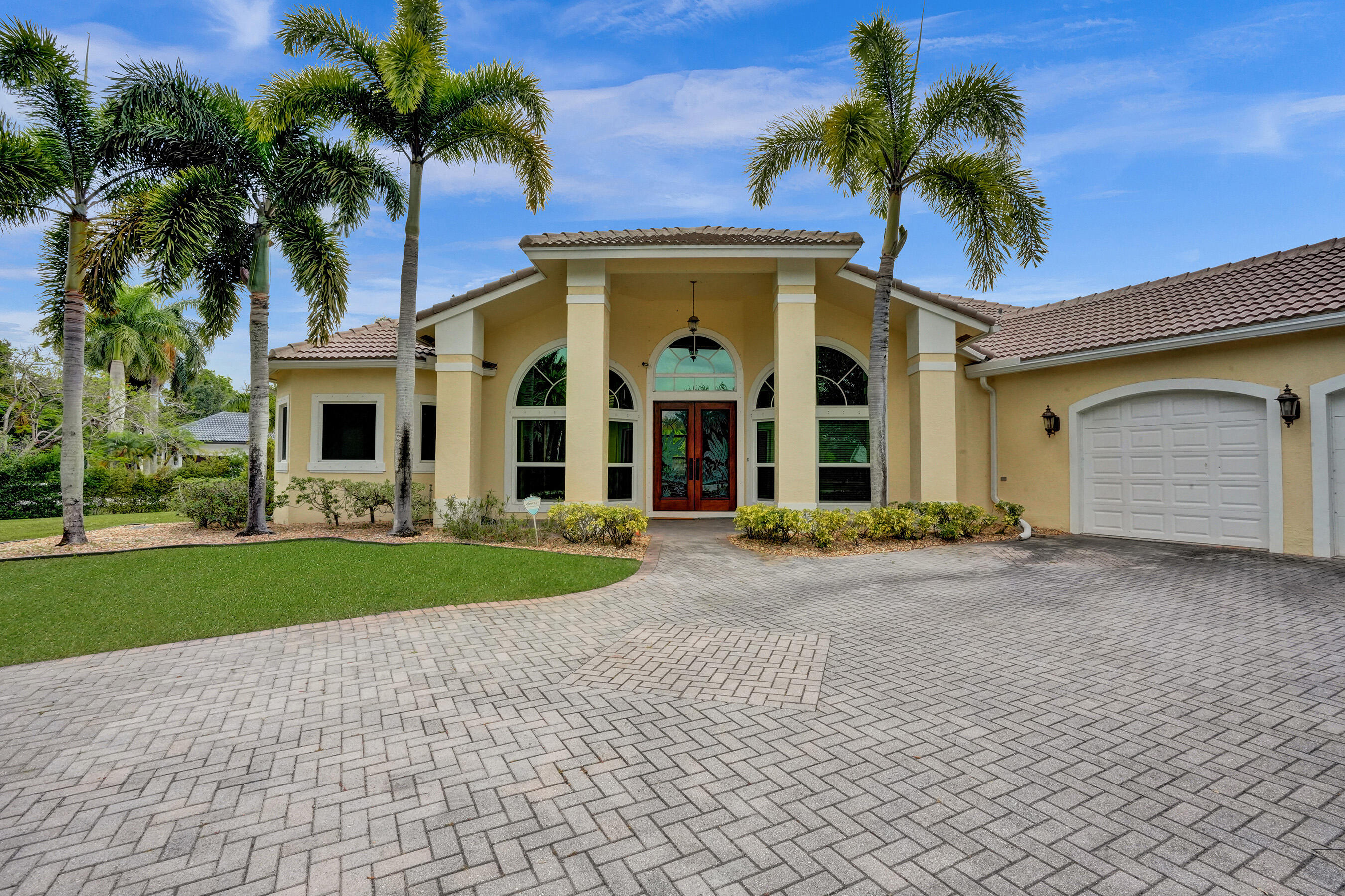 front view of a house with a yard and palm trees