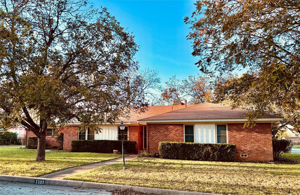 a front view of house with yard and trees around