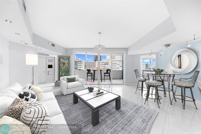 a living room with furniture a rug kitchen view and a large window