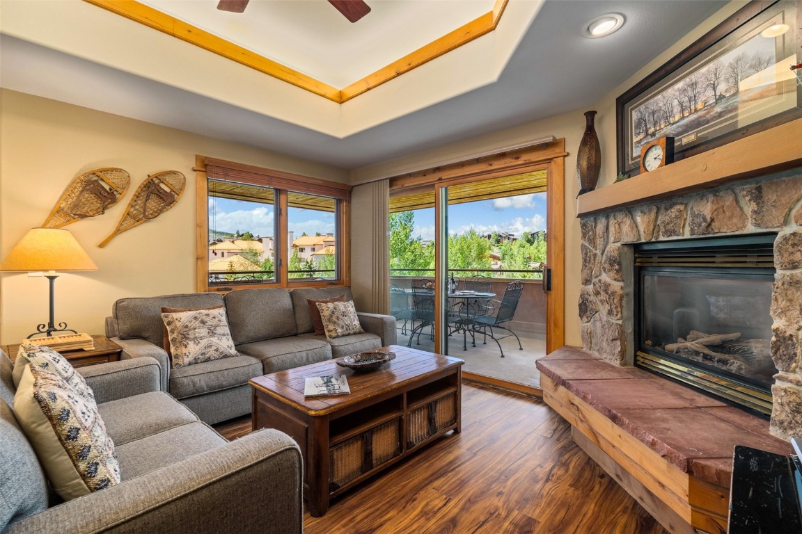 Living room featuring dark hardwood / wood-style floors, ceiling fan, a raised ceiling, and a fireplace