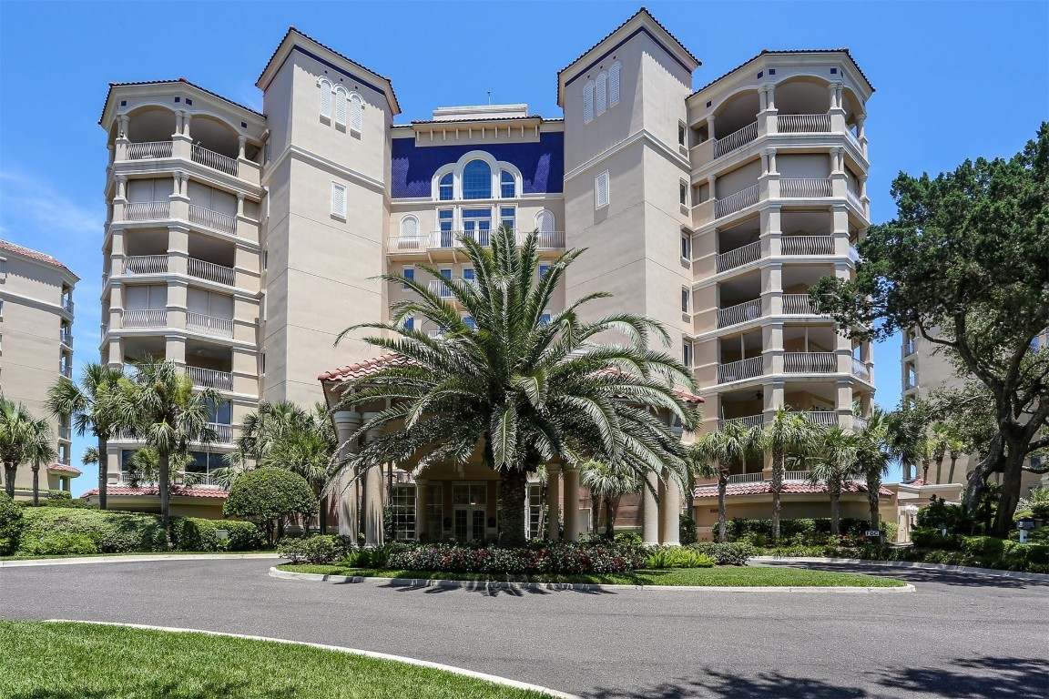 a front view of multi story residential apartment building with yard and parking space