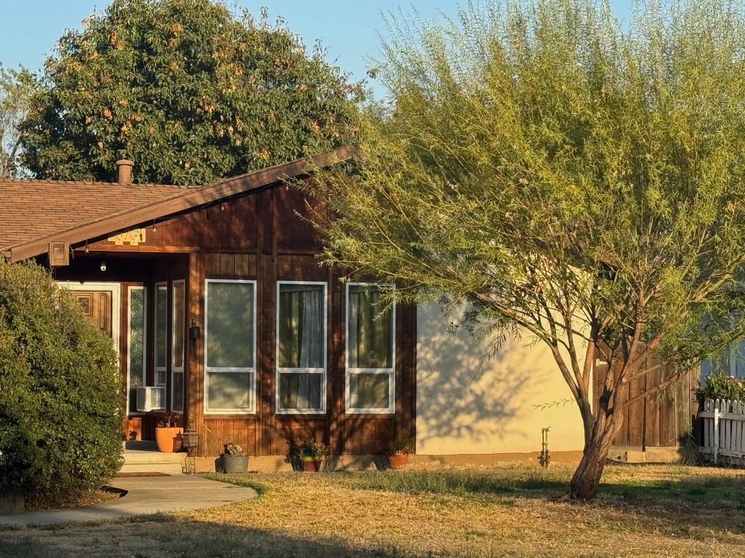 a small barn in front of a yard with plants and trees