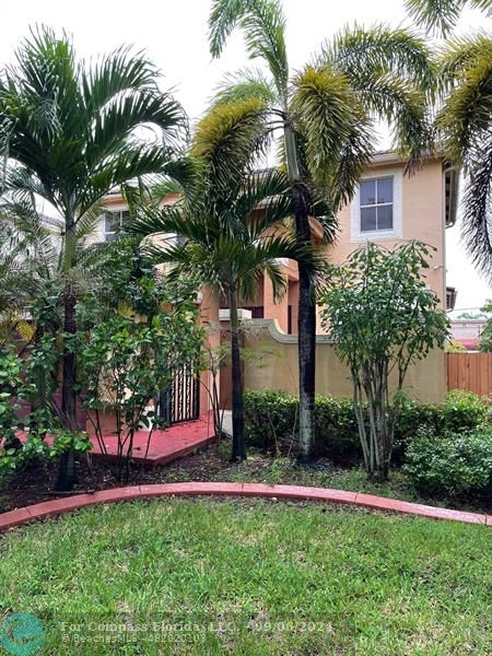 a view of a house with a yard and palm trees