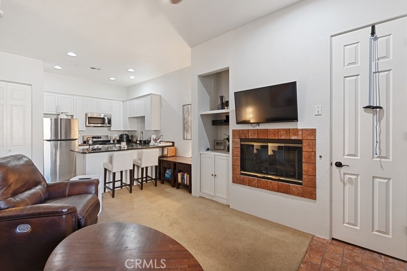 a living room with stainless steel appliances kitchen island granite countertop a stove a refrigerator a oven a dining table and chairs with wooden floor