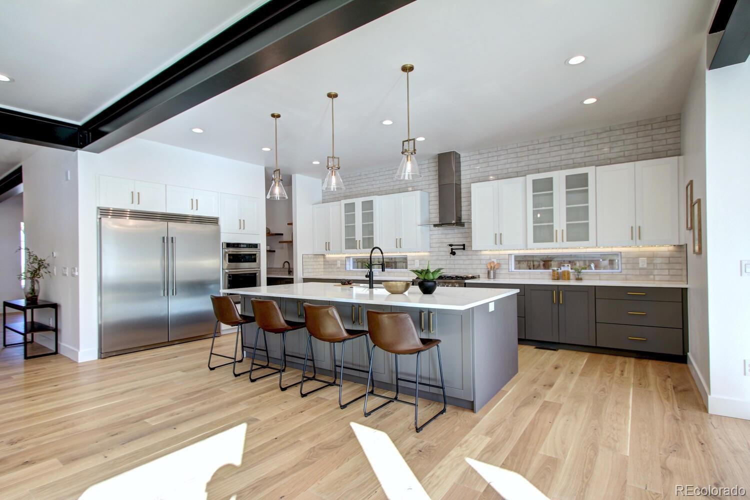 a large kitchen with kitchen island a large counter space wooden floor stainless steel appliances and windows