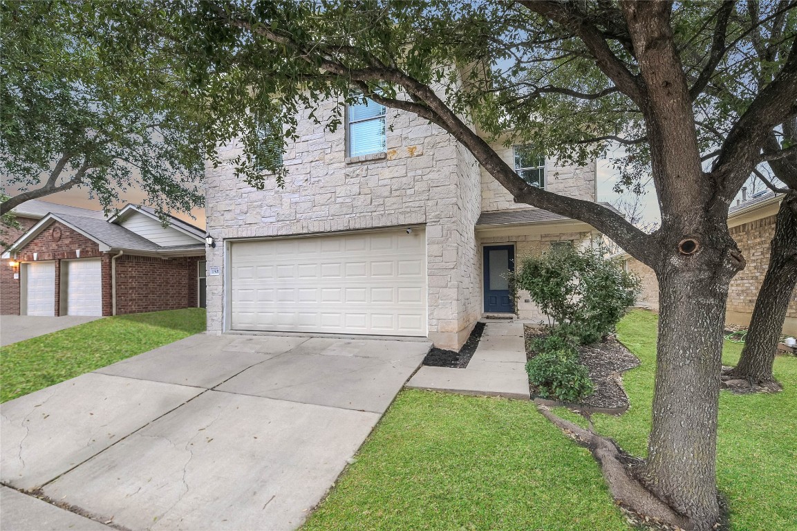 a front view of a house with a yard and a tree